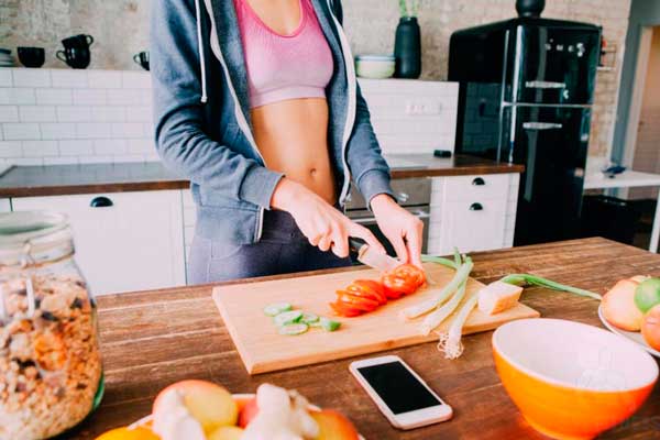 Mulher preparando refeição para depois do treino, seguindo sua dieta low carb